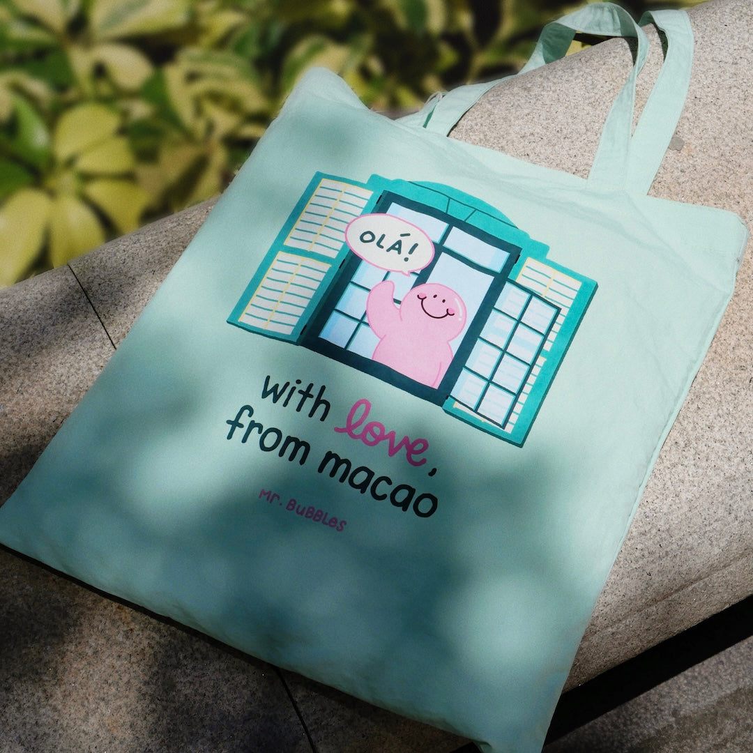 Mr.Bubbles character peeking from Macau green colonial building on mint tote bag